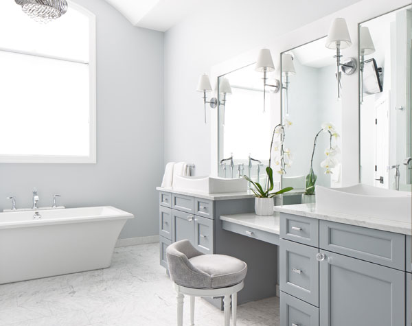 white and gray bathroom with bathrub in background, mirrors on wall with lights overhanging